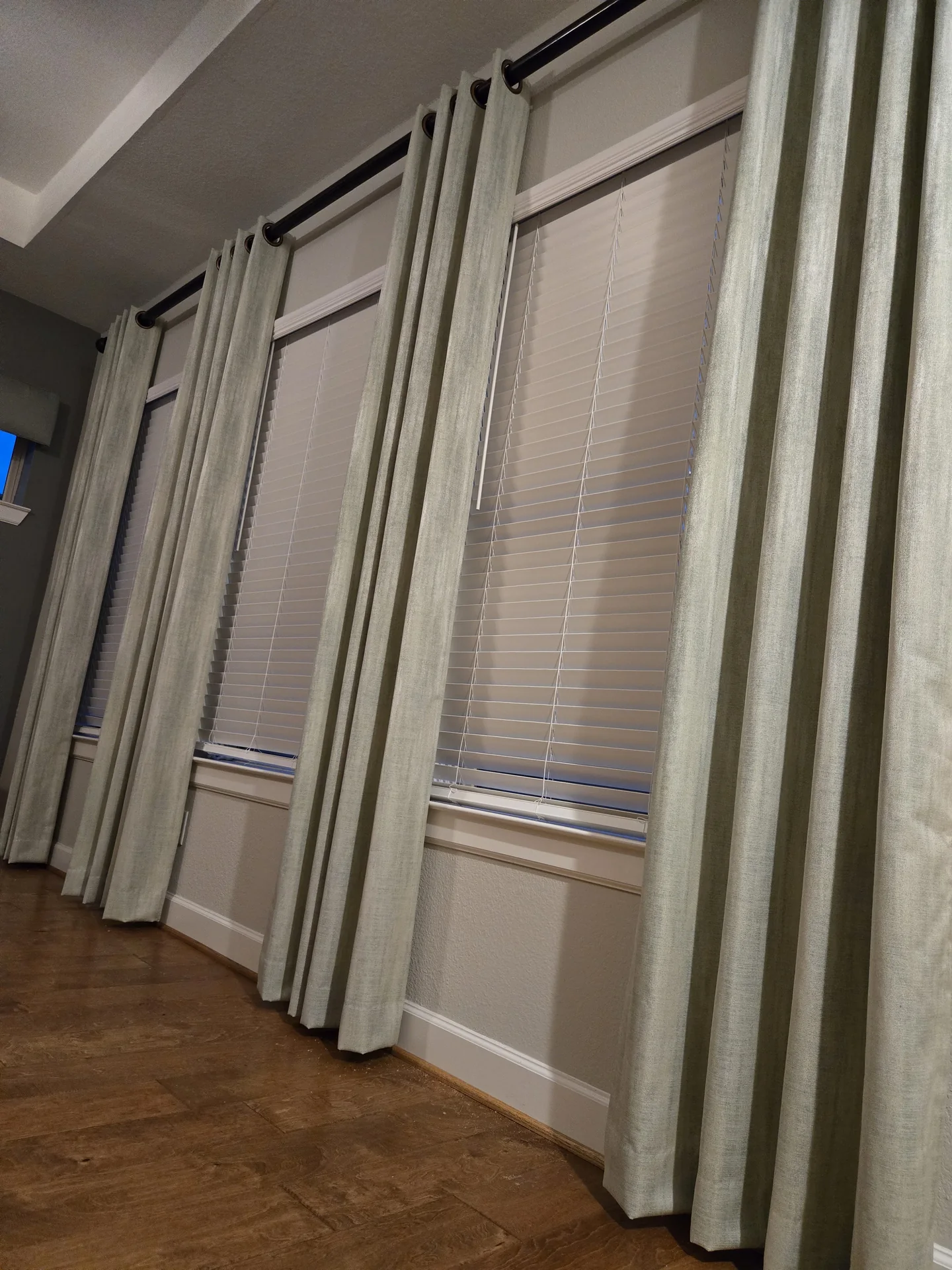 Bedroom with drapes and wood blinds — The Blinds Tech